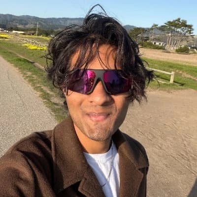 A sunny outdoor selfie in sunglasses and a brown jacket.