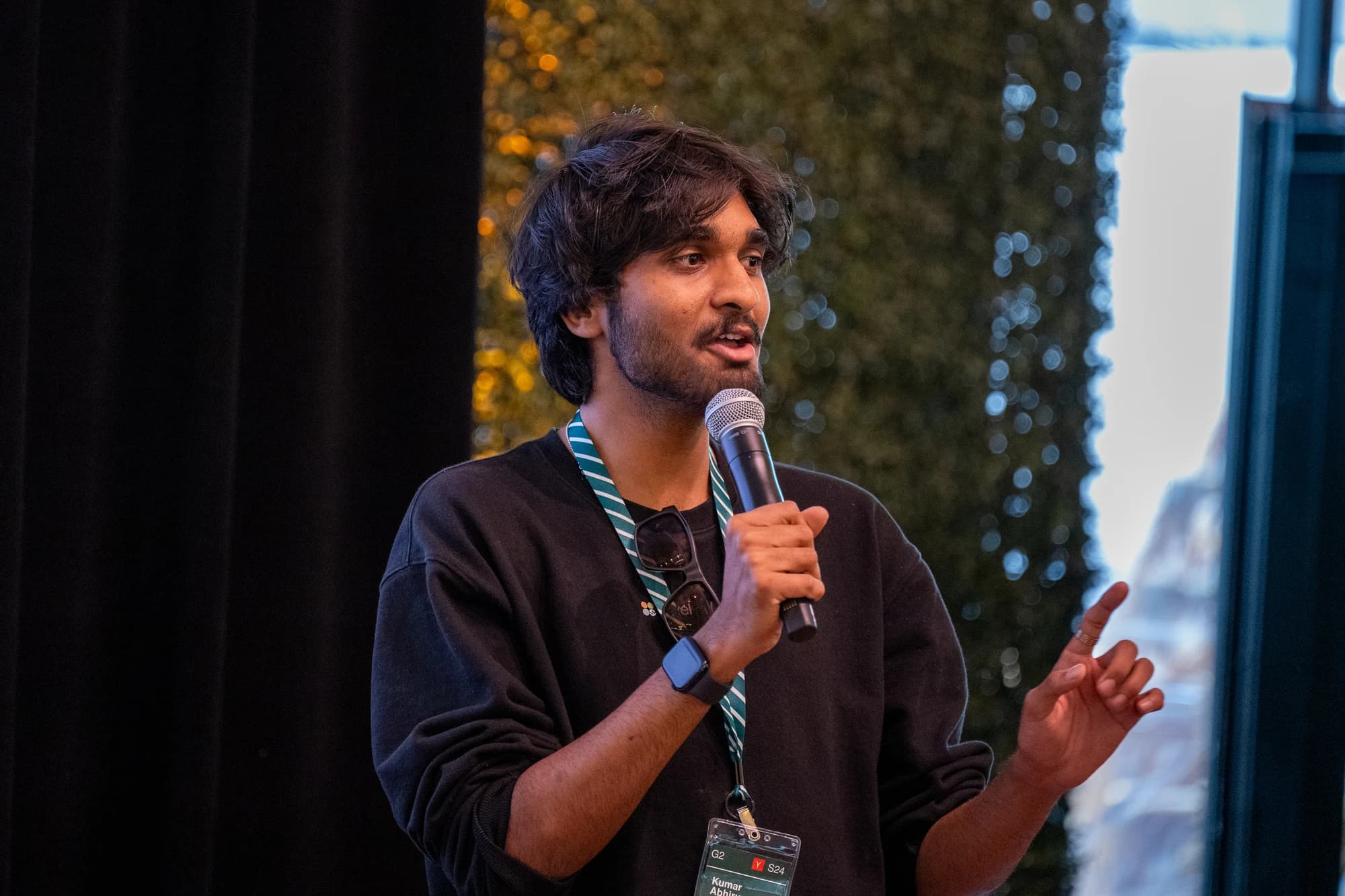 Speaking into a microphone while wearing a YC S24 badge.